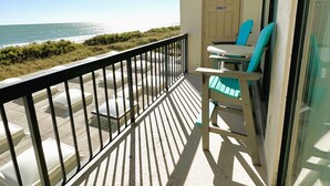 Een balkon met uitzicht op de oceaan, een deur met de tekst 'OWNERS' en een tafel met stoelen.