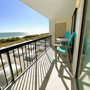 Un balcone con vista sull'oceano, una porta con la scritta 'OWNERS' e un tavolo con sedie.