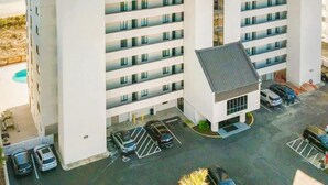 Een meerhoog hotel met een parkeerplaats en uitzicht op het strand.