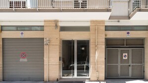 Um edifício com duas portas de garagem fechadas, cada uma delas com uma placa de 'Proibido Estacionar'.