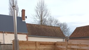 A wooden hot tub with a metal frame, surrounded by a wooden deck and a brick wall.