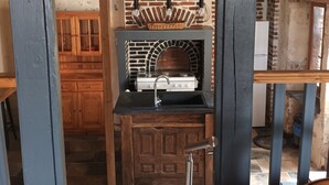 A kitchen with a brick wall, a stove, and a sink.