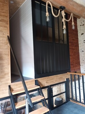 Un intérieur moderne avec un escalier en bois, des rampes noires et un mur d’escalade.