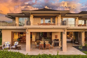 Una casa de dos pisos con balcón, zona de estar al aire libre y patio.