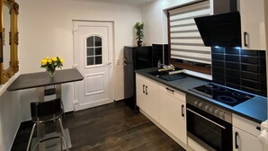 A modern kitchen with a black stove, white cabinets, and a wooden floor. - Hearty vacation apartment with a warm ambience in a private location (Delmenhorst)