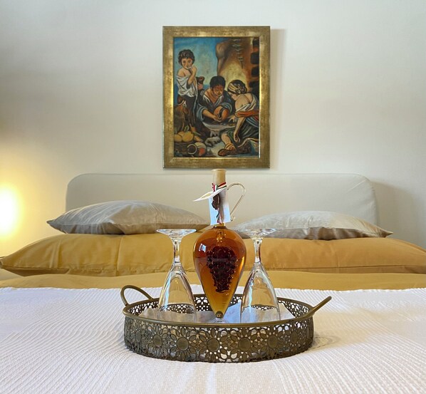 Un lit avec un plateau décoratif devant, un tableau au mur et une lampe sur la gauche.