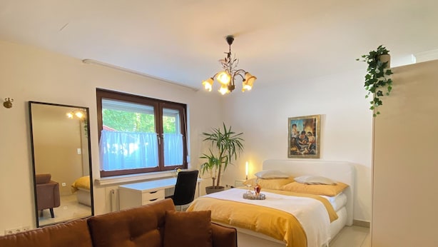 A modern bedroom with a bed, a sofa, a desk, and a chair. - Hearty vacation apartment with a warm ambience in a private location (Delmenhorst)