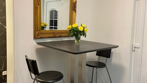 A dining area with a dark wooden table, two black chairs, a gold-framed mirror, and a vase with yellow flowers. - Hearty vacation apartment with a warm ambience in a private location (Delmenhorst)
