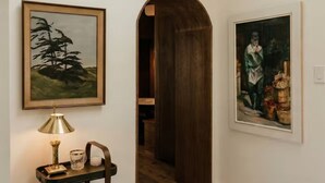 Un pasillo con dos cuadros enmarcados, una mesa con una lámpara y una puerta de madera.