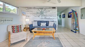 A living room with a sofa, coffee table, and a rug with a whale design. - Directly on the Gulf - Unit  6 - 1 Bedroom - Ground Floor - Sleeps 4 (Venice)