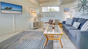 A living room with a sofa, a coffee table, a rug, and wall art. - Directly on the Gulf - Unit  6 - 1 Bedroom - Ground Floor - Sleeps 4 (Venice)