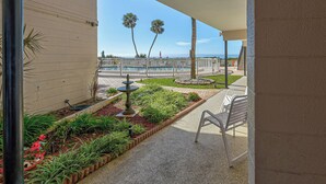 A covered outdoor area with a pool, palm trees, and a garden. - Directly on the Gulf - Unit  6 - 1 Bedroom - Ground Floor - Sleeps 4 (Venice)