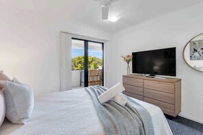 Una camera d'albergo con un letto, una televisione, un comò e una porta finestra che dà su un balcone.