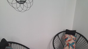 Two black wire-framed chairs with colorful floral cushions, a small round table, and a wall-mounted mirror.