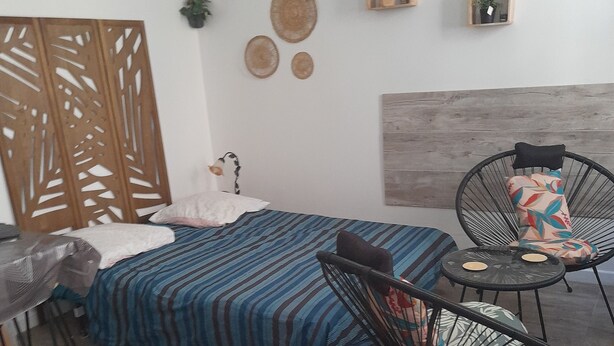 A bedroom with a bed, two chairs, a small table, and wall decorations.