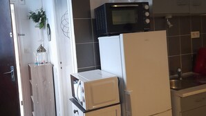 A compact kitchen with a microwave, a refrigerator, and a sink. A sign on the wall reads "Collect MOMENTS not THINGS."