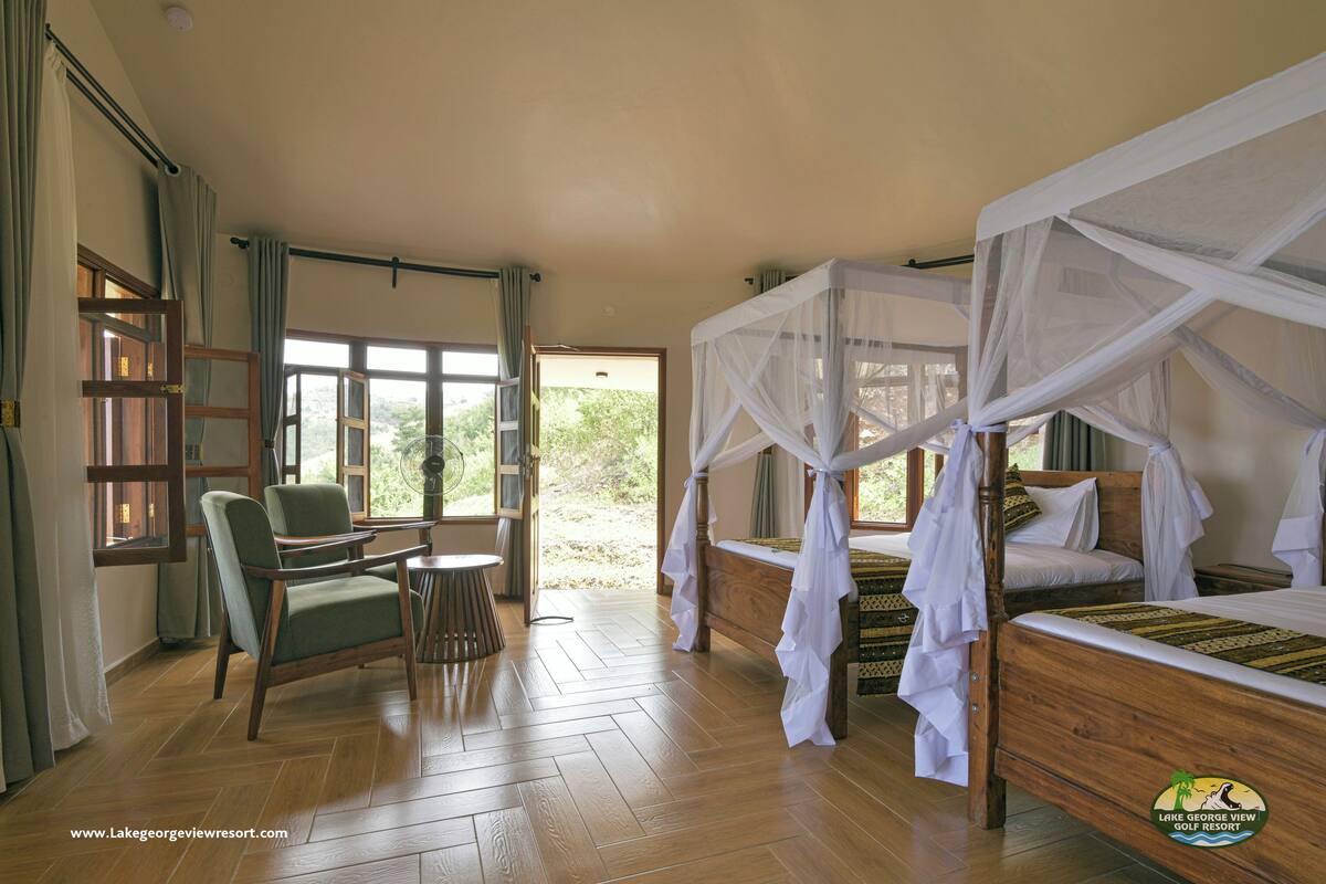 A room with two beds, a chair, a table, and a window with curtains.