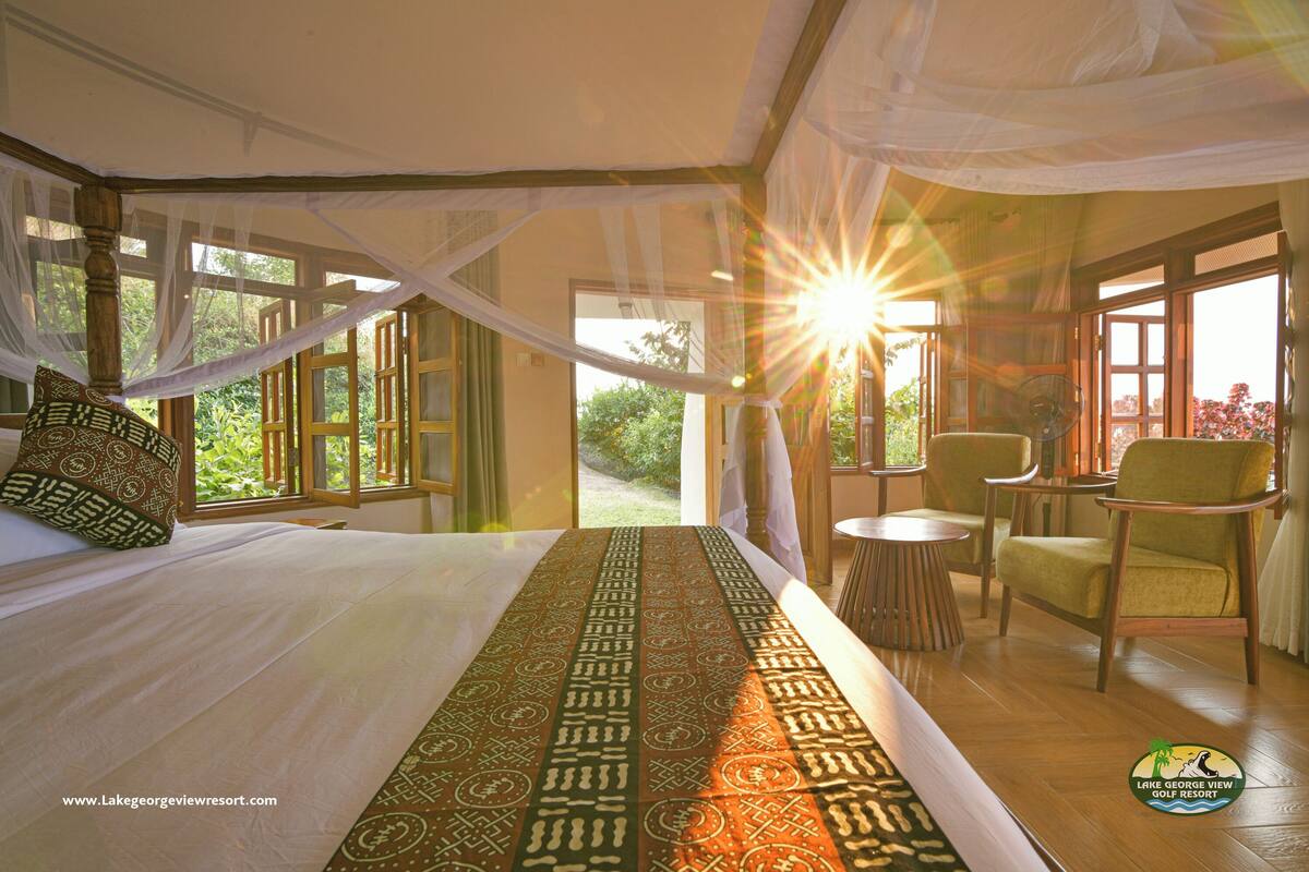A bedroom with a large bed, a patterned runner, and a view of the outdoors.