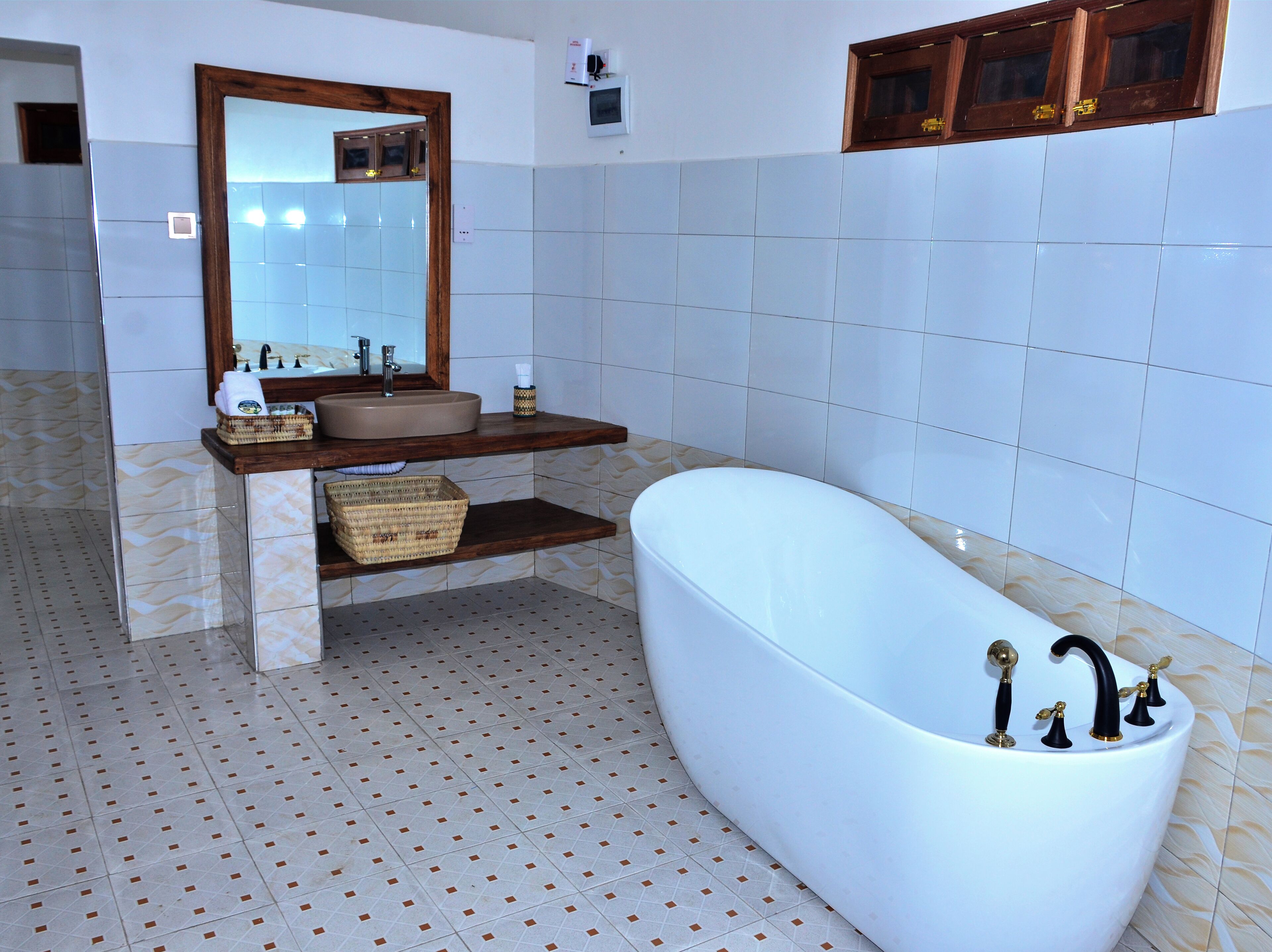 Ein Badezimmer mit freistehender Badewanne, einem Waschtisch mit Spiegel und einem Fliesenboden.