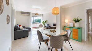 Un salon moderne avec une table à manger en verre, un canapé gris et un meuble vert.