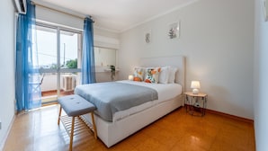 Une chambre à coucher comprenant un lit, un banc, une table de chevet et donnant sur l’extérieur.