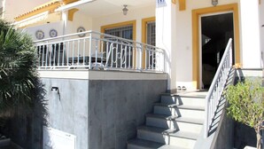 Un edificio con fachada blanca, detalles en amarillo y un balcón con barandilla metálica.
