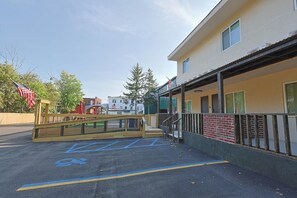 A parking area with handicapped parking spaces, a wooden bridge, and a building with a ramp and a covered entrance. - Rodeway Inn Monticello, New York (Monticello)