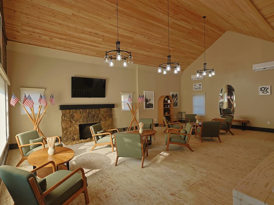 A spacious living room with a stone fireplace, multiple seating arrangements, and a large flat-screen TV mounted on the wall.