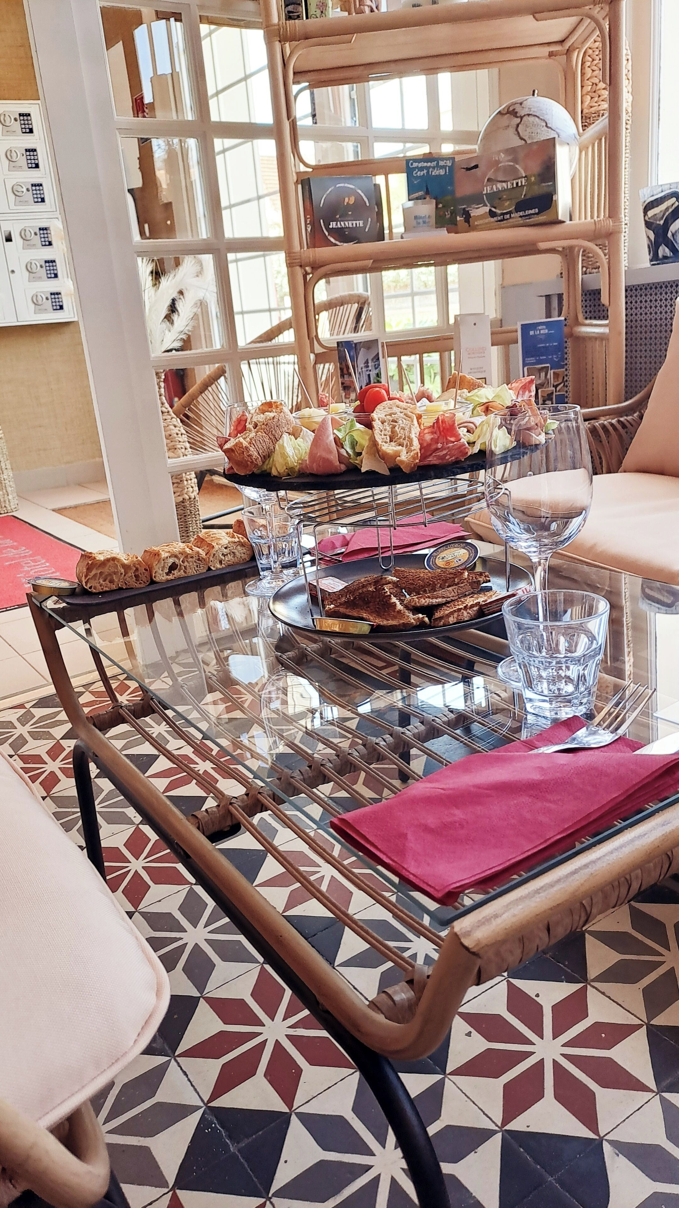 Una mesa con cubierta de vidrio, varios alimentos y una copa de vino.