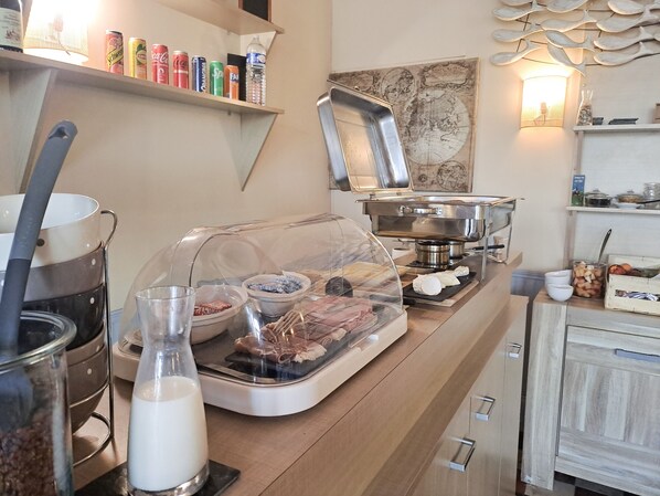 Een ontbijtbuffet met diverse gerechten, een koffieapparaat en een decoratief wandobject.