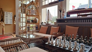 A cozy room with wicker furniture, a chessboard, and a bookshelf. - Hotel de la Mer (Blonville-sur-Mer)