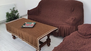 Un salon avec un canapé marron, un pouf assorti et une table basse agrémentée d’un objet décoratif.