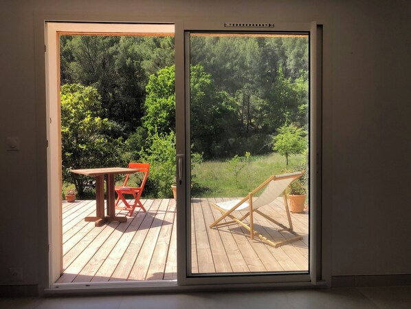 A room with a sliding glass door leading to an outdoor deck with a wooden table and chairs.