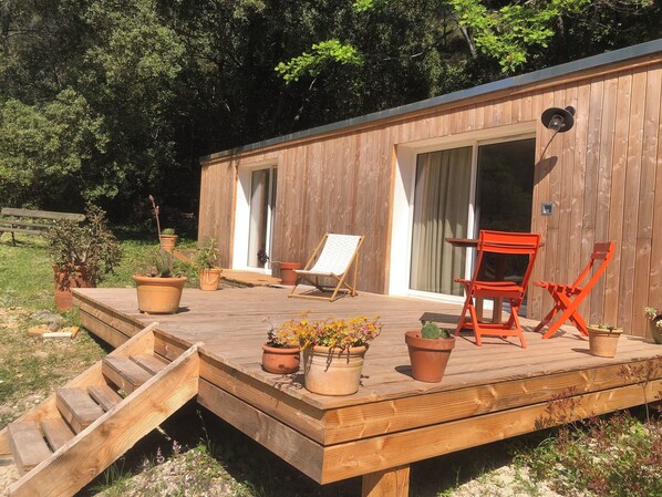 A wooden deck with a chair, a small table, and potted plants.