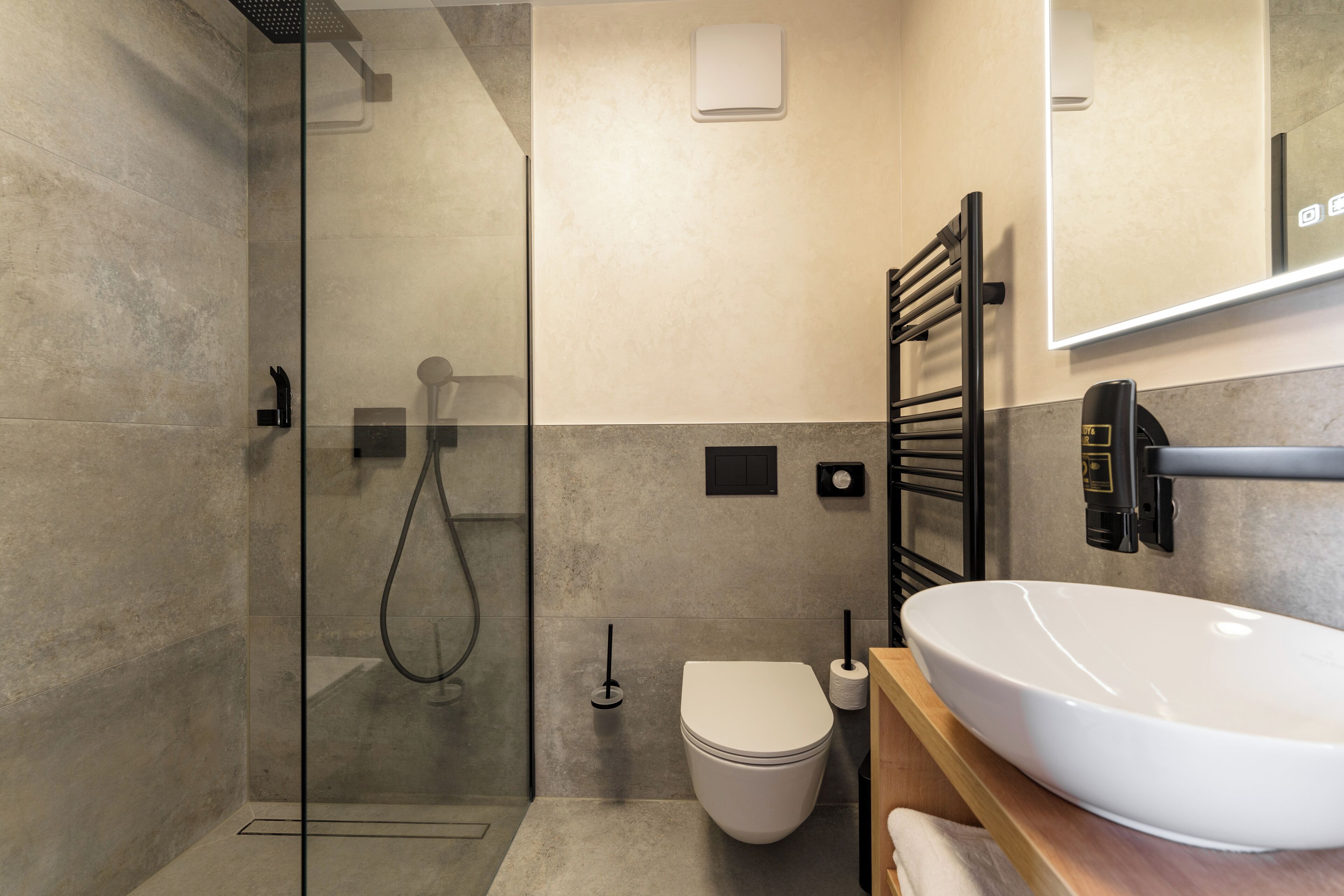 Un bagno moderno con cabina doccia in vetro, un water bianco e un ampio lavandino con specchio soprastante.