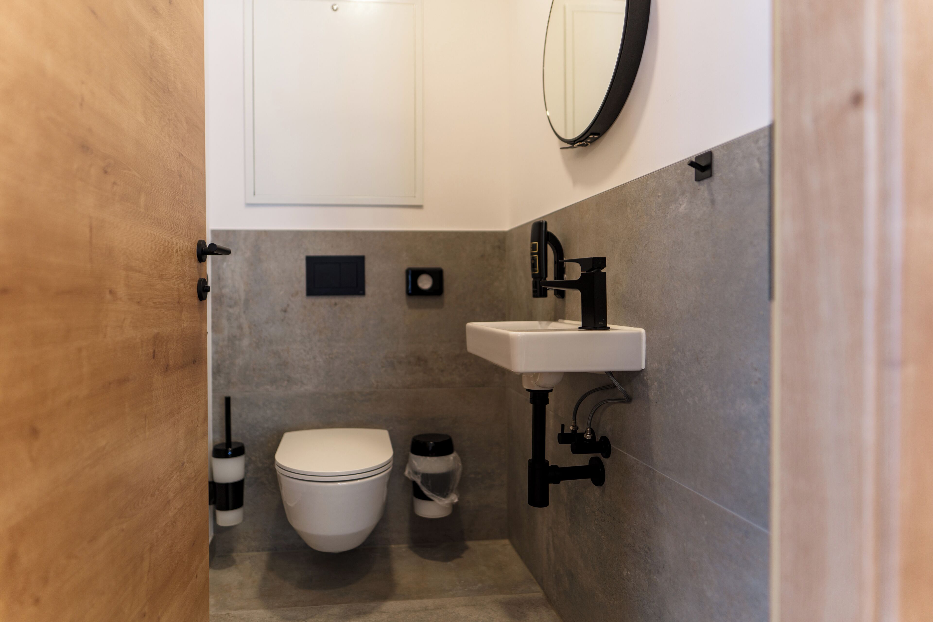 A compact bathroom with a toilet, a sink, and a mirror.