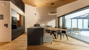 Eine moderne Küche mit Einbauofen und Essbereich mit Holztisch und Stühlen.
