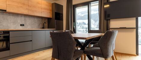 A modern kitchen with grey cabinets, a wooden countertop, and a dining area with a table and chairs.