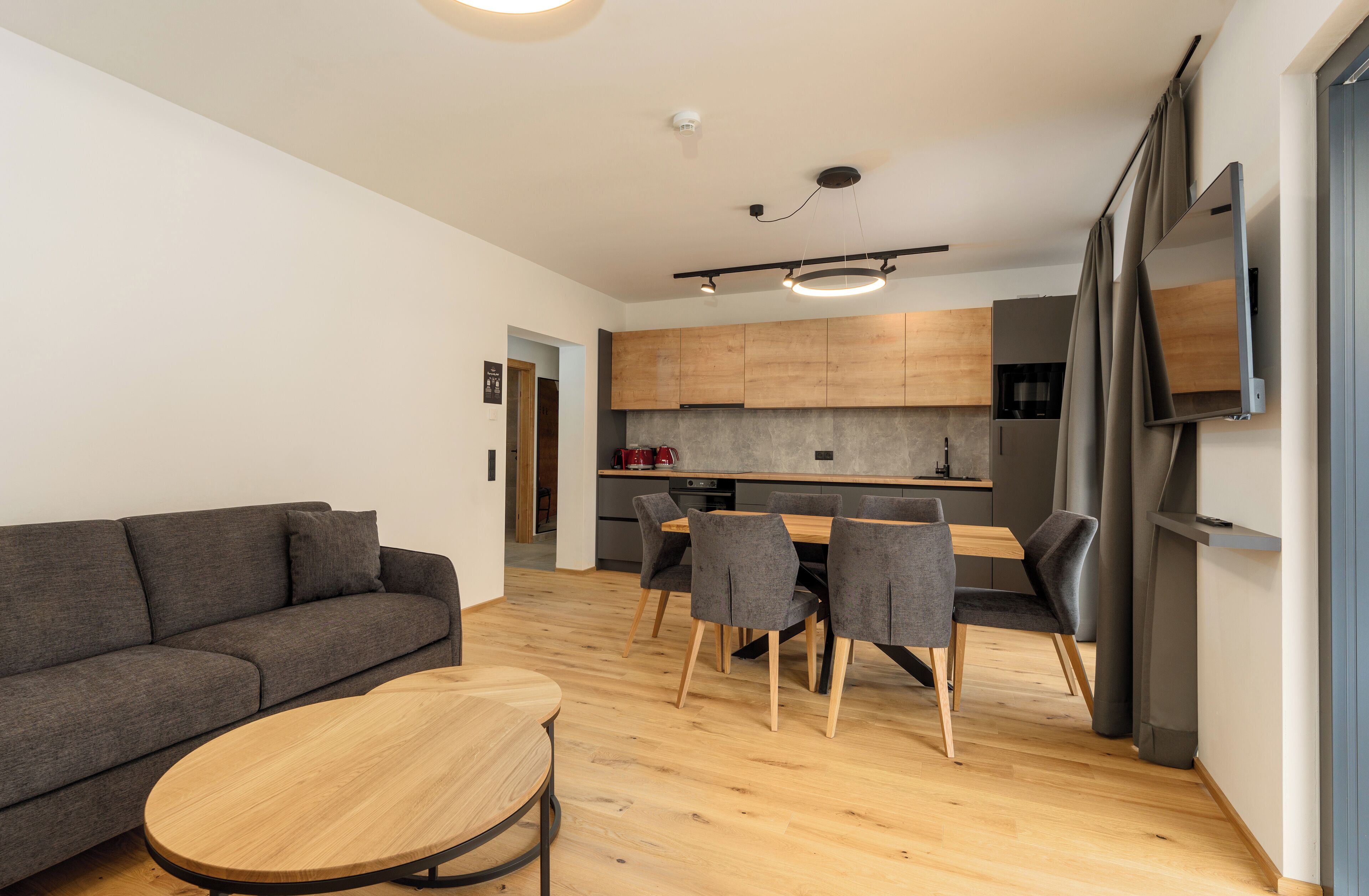 A modern living room with a sofa, a round coffee table, and a dining area with chairs and a table.