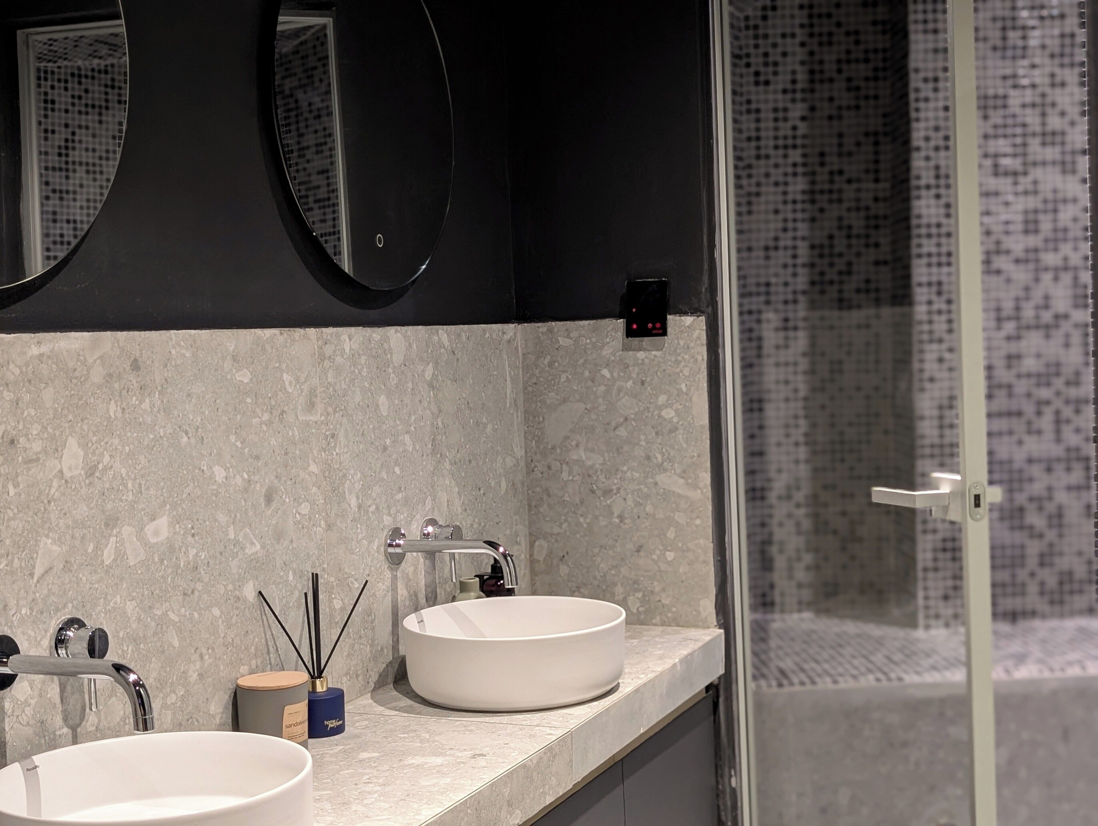 A bathroom with two sinks, a mirror, and a shower area.