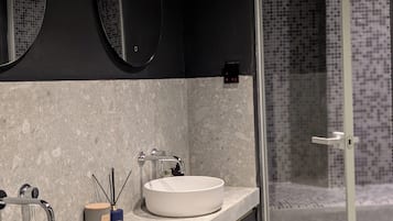 A bathroom with two sinks, a mirror, and a shower area.