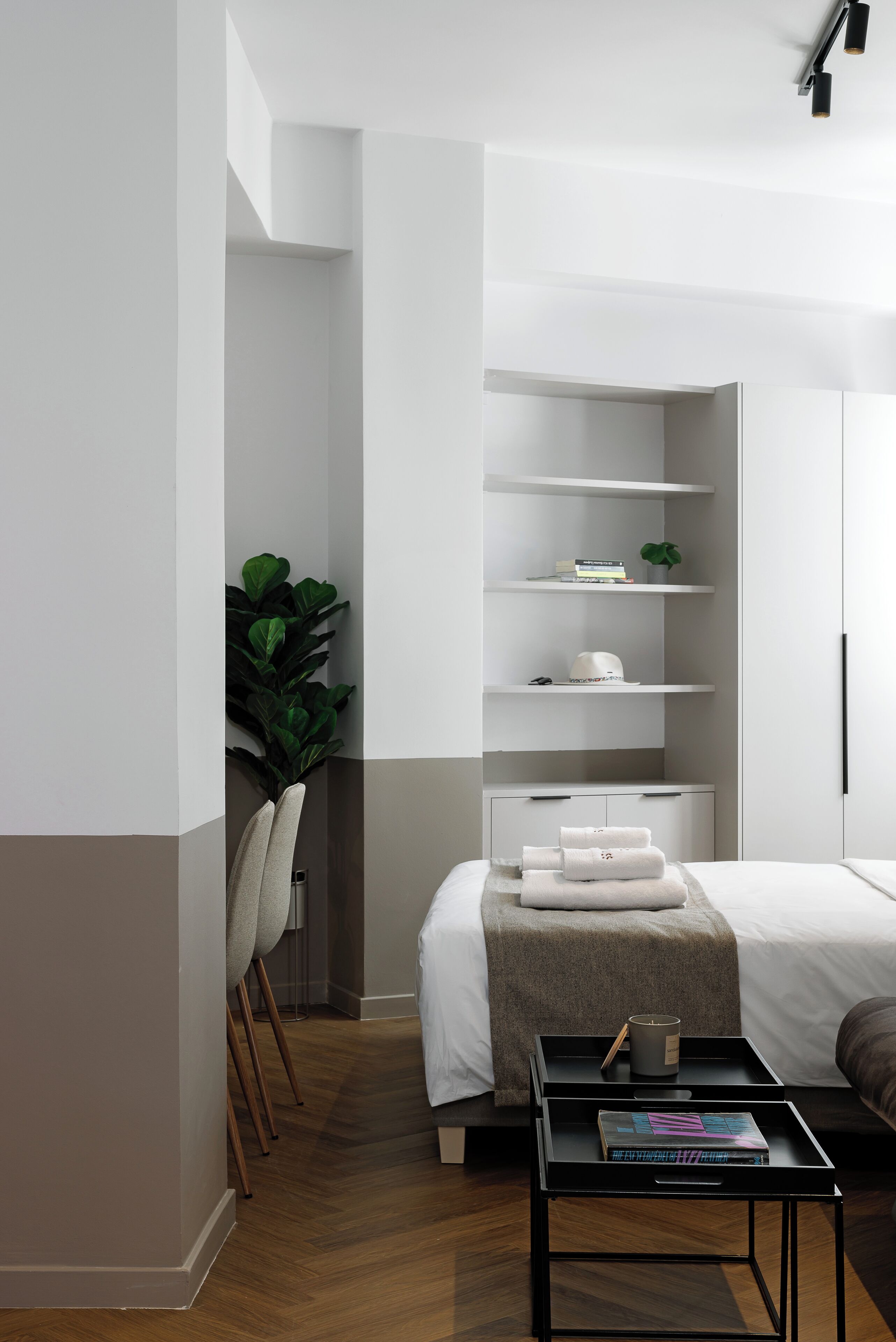 Una camera da letto moderna con un letto, comodini, una libreria a incasso e una pianta in vaso.