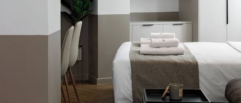 Ein modernes Schlafzimmer mit Bett, Nachttischen, einer eingebauten Regallösung und einem Blumentopf.