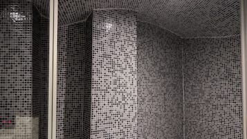 A bathroom with mosaic tile walls and floor, a bench, and a shower area.