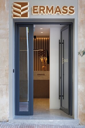 L’entrée d’un hôtel au design moderne, avec une porte en verre et une enseigne indiquant « ERMASS ».