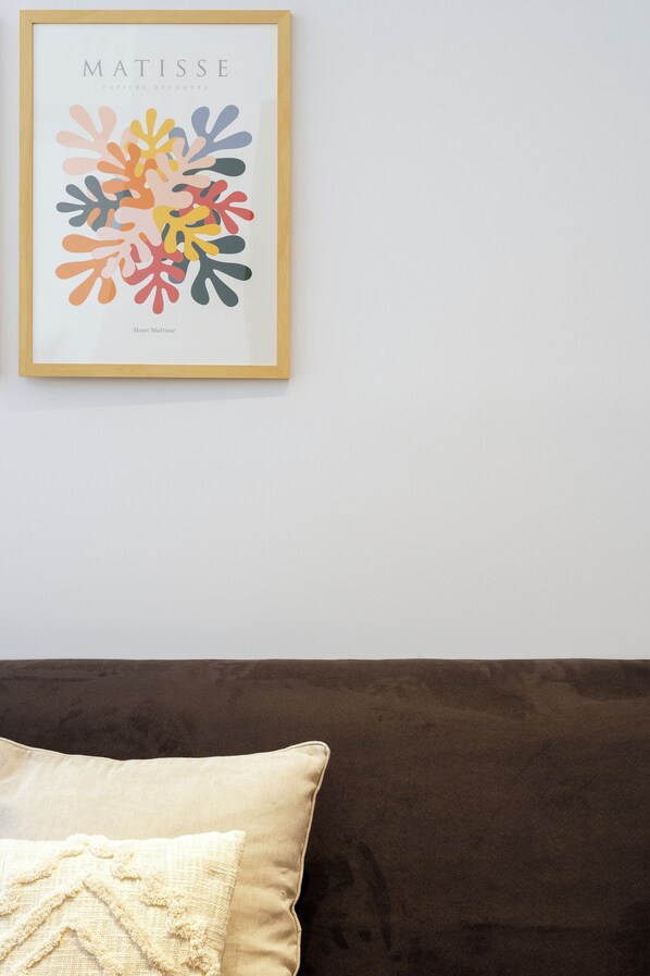A framed artwork titled 'Matisse' on a white wall above a brown sofa with a beige cushion. - ERMASS Athens (Athens)