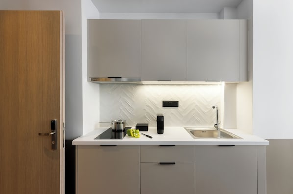 Una cocina moderna con encimera blanca, pileta de acero inoxidable y gabinetes grises.