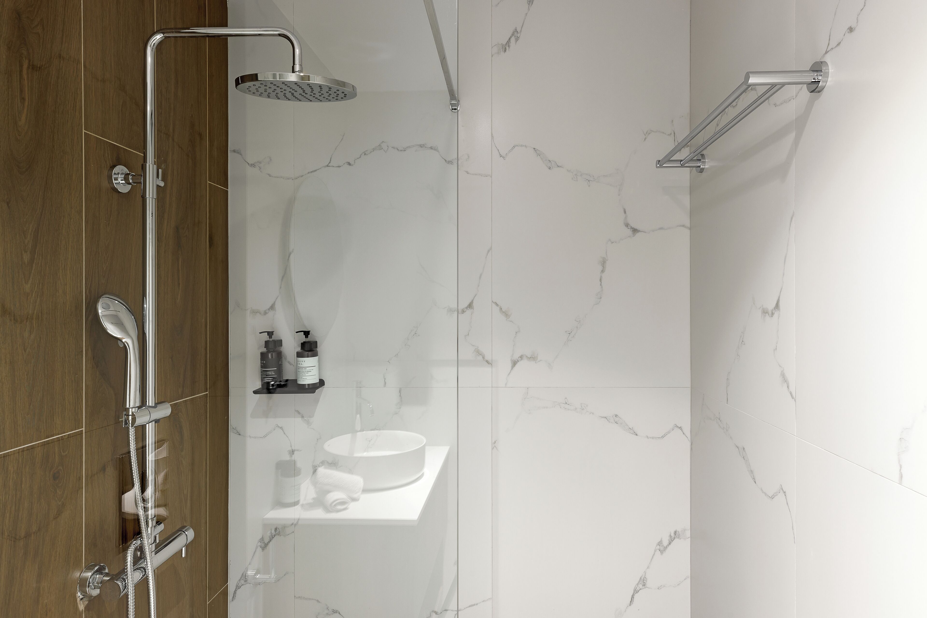 Un baño moderno con ducha, lavamanos y artículos de aseo en una repisa.