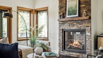 A living room with a stone fireplace, large windows, and a round coffee table.