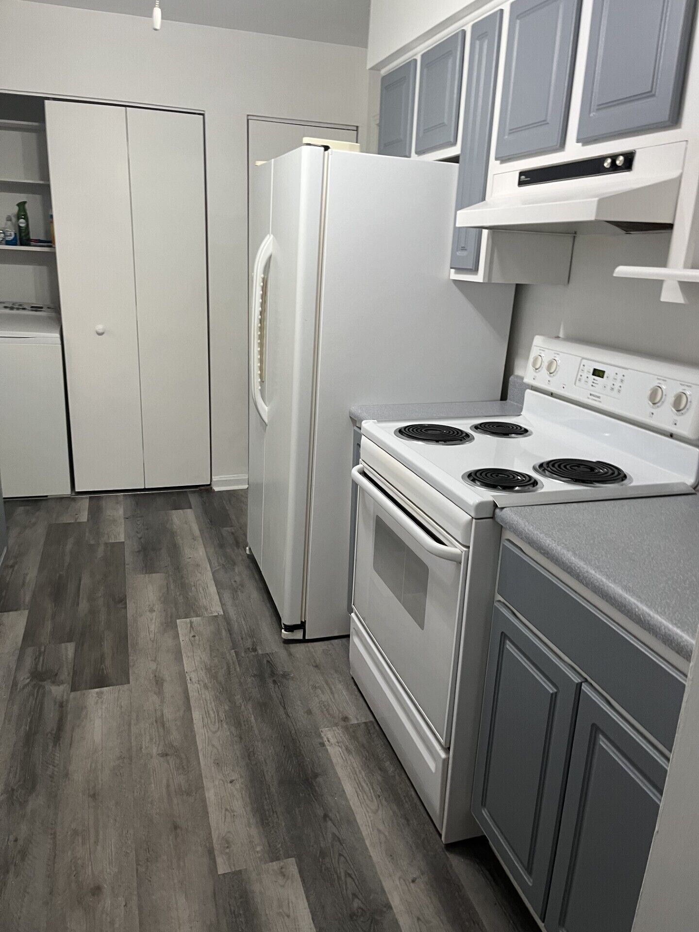 A compact kitchen with a refrigerator, stove, and cabinets.